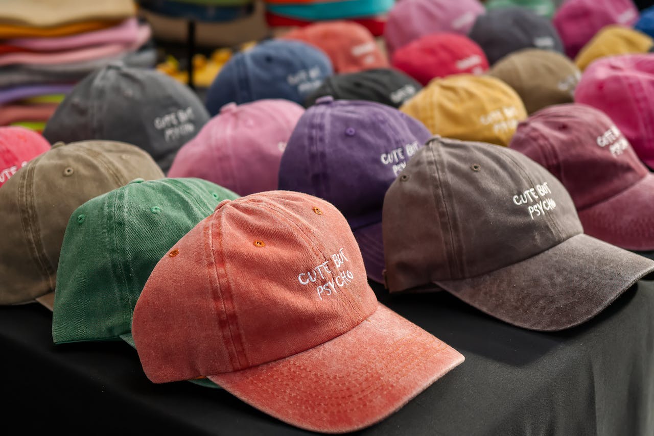 Close-up of colorful baseball caps with embroidered text at an outdoor market in England.
